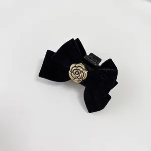 Velvet bow hair clip with golden camellia flower accent for elegant hair styling