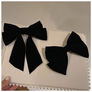 Detail of vintage black velvet bow hair clips with long ribbons on a pearl display board
