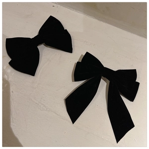 Macro shot of black velvet bow hair clips featuring long ribbons and thick luxury texture