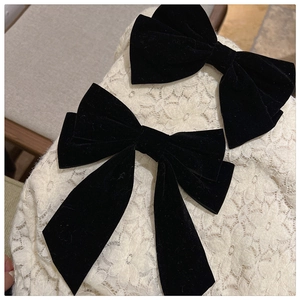 Close-up of black velvet bow hair clips with long ribbons on elegant white lace fabric