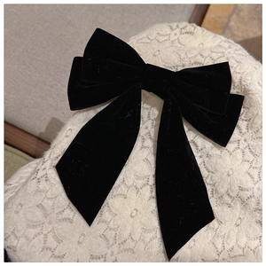 Close-up of elegant black velvet double bow hair clip on white lace fabric background