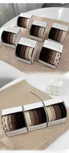 Gros plan d'élastiques à cheveux tressés tons terre sur cartes en papier chic