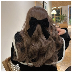 Detail of vintage black velvet bow hair clip with long ribbons on wavy brown hair