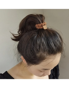 Détail d'un chouchou en maille marron avec une étiquette décorative en cuir artisanal