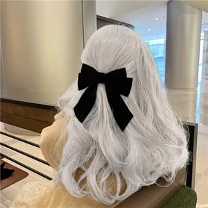 Elegant large black velvet double bow hair clip styled on wavy hair for a chic look