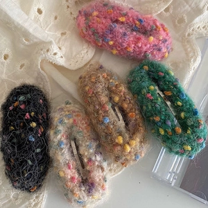Macro detail of 5-piece colorful knitted wool hair clips set on lace fabric
