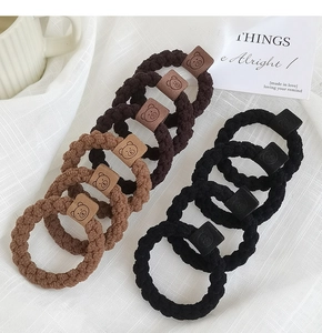 Détail d'élastiques à cheveux tressés noirs et marrons avec mignons patchs d'ours