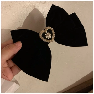 Detail of black velvet bow hair clip featuring a heart-shaped camellia rhinestone centerpiece