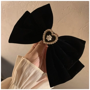 Macro detail of large black velvet bow hair clip with camellia heart rhinestone accent