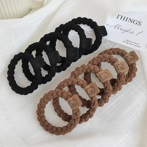 Détail des chouchous tressés en noir et marron avec de petits motifs d'ours mignons