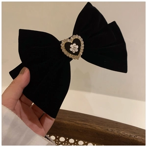 Close-up of black velvet bow hair claw featuring a white camellia heart centerpiece