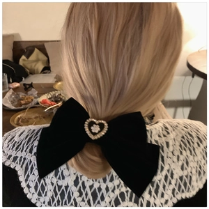 Detail of a large black velvet bow hair clip with pearl heart center on blonde hair