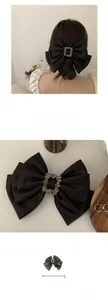 Detail showing the 18cm black satin bow hair clip with a square rhinestone center