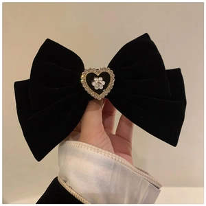 Close-up of black velvet bow hair claw featuring a golden heart with camellia detail