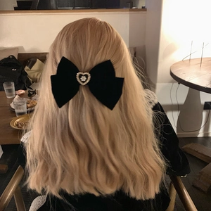 Large black velvet bow hair claw clip with pearl heart detail on blonde wavy hair