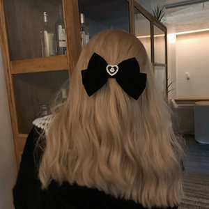Elegant black velvet bow hair clip with pearl heart detail on model's wavy hair