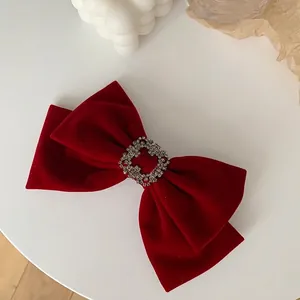 Detailed view of the red velvet bow hair clip with a sparkling square rhinestone center