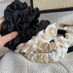 Detailed view of black and cream pleated satin headbands with rich textured ruffles
