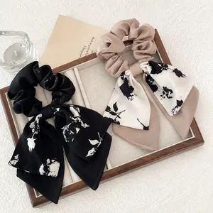 Floral silk scrunchies with long ribbons in black and brown, set on a jewelry tray
