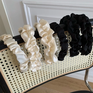 Detailed view of black and cream pleated satin headbands on a vintage rattan chair backrest