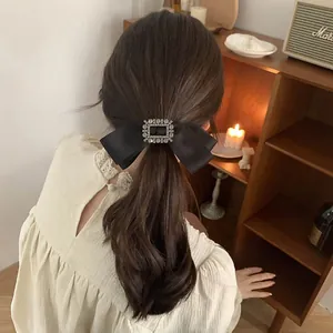 Détail d'un nœud en satin noir avec boucle en strass étincelante porté sur cheveux de femme