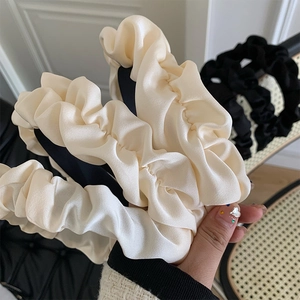 Detail of elegant black and off-white pleated satin headbands with glossy finish