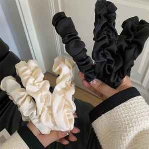Detail of silk-like pleated headbands in black and cream with voluminous texture