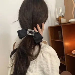 Détail d'un nœud en satin noir avec boucle en cristal étincelante sur une queue de cheval