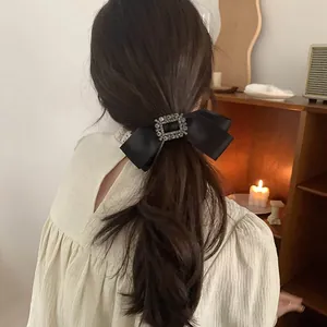 Détail d'un nœud papillon en satin noir avec une boucle carrée sertie de strass brillants