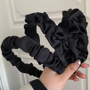 Macro detail of the black pleated scrunchie headband showing satin fabric texture