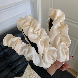 Close-up of cream white ruffled satin headband with elegant silk texture and cloud design