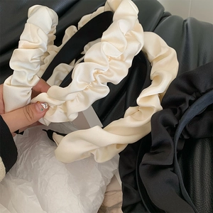 Detail of off-white ruched satin headband with elegant pleated fabric texture