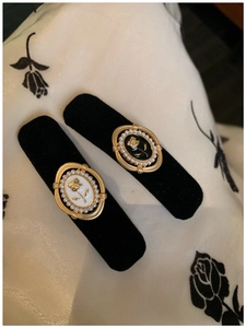 Close-up of velvet hair clips featuring golden rose relief and faux pearl trim