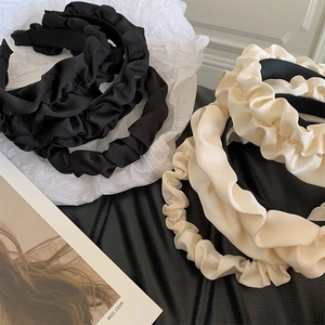 Detail of black and cream pleated satin headbands with elegant silk texture on prop cards