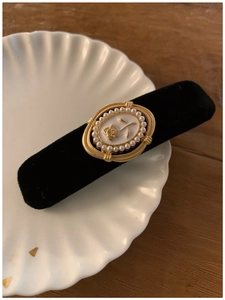 Close-up of vintage black velvet hair clip with golden rose and pearl embellishments