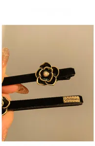 Dettaglio di un fermaglio per capelli in velluto con camelia nera e perla al centro