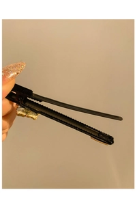 Dettaglio di un fermaglio per capelli vintage in tessuto nero con farfalle dorate