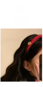 Détail d'un serre-tête en satin bordeaux de 1,5 cm avec une fleur de camélia dorée