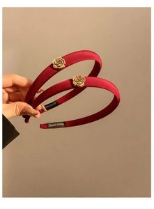 Gros plan de serre-têtes en satin rouge faits main avec fleurs de camélia dorées élégantes