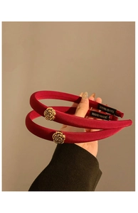 Détail de serre-têtes en satin rouge foncé avec roses dorées et étiquette artisanale