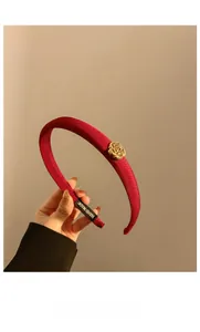 Gros plan détaillé du serre-tête en satin rouge foncé avec fleur de camélia dorée élégante