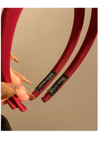 Gros plan sur le serre-tête en satin bordeaux avec étiquette HAND MADE dorée