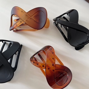 Detail showing four assorted large hair claws in matte amber, black, and gloss finishes