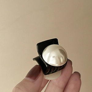 Detailed view of a French vintage mini hair claw clip with glossy black finish and large pearls