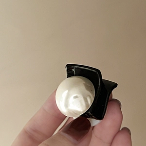 Macro shot of black resin hair claw clip with a large pearl detail and metal spring