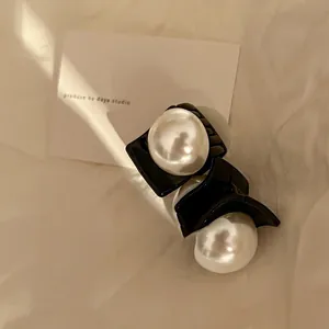 Close-up of elegant French vintage pearl hair clip with black resin base and satin sheen