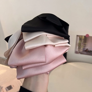 Dettaglio di eleganti fermagli a fiocco in raso nero, champagne e rosa loto