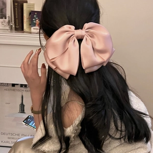 Fermaglio per capelli con fiocco di raso rosa indossato sui capelli lunghi lucidi
