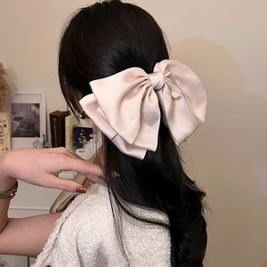 Vista posteriore di un grande fiocco di raso champagne sui capelli di una modella