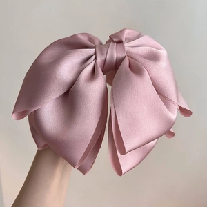 Dettaglio del cerchietto in raso rosa con trama lucida ed elegante fiocco multistrato